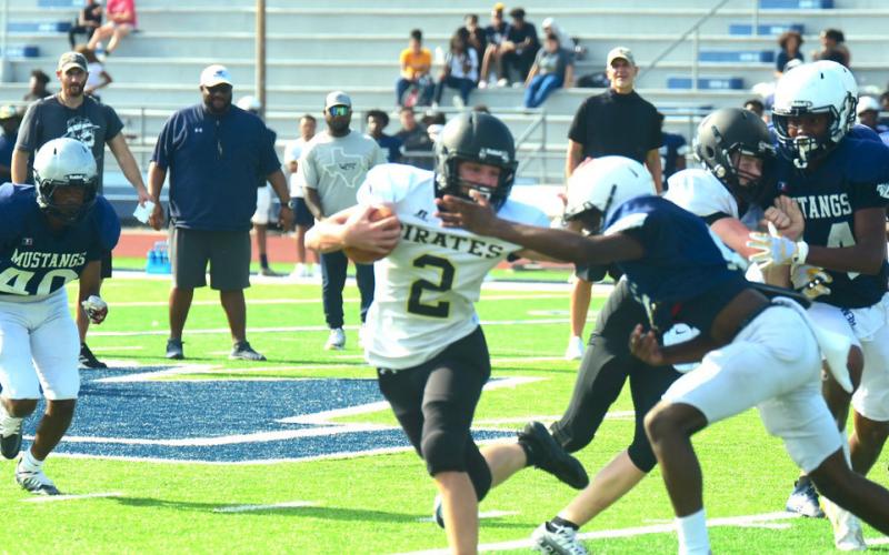 Junior varsity Pirate Brody Bloss looks for running room outside as a Mustang defender tries to stop him.