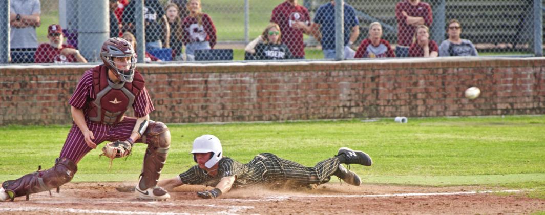 A Pirate slides into home head first to bat the pith to home.