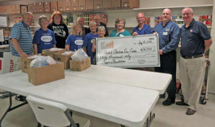 Representatives of the Southeast Texas Food Bank and Feeding America (right) hand a check for $30,000 in grant funds to volunteers (left) at the United Christian Care Center. These funds are intended to help the U.C.C.C. in their ongoing recovery from Hurricane Harvey. Archive Photo