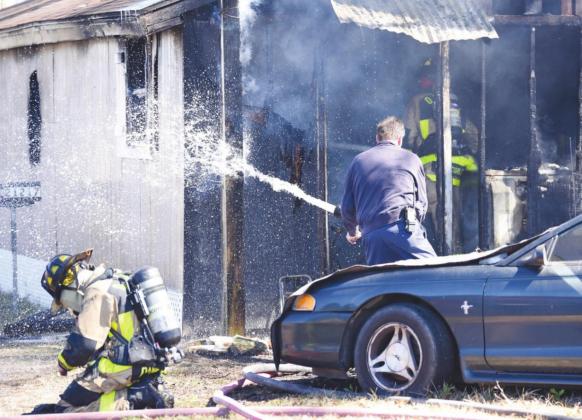 OCESD#1 firemen enter the burning residence as a colleague sprays remaining hot spots.