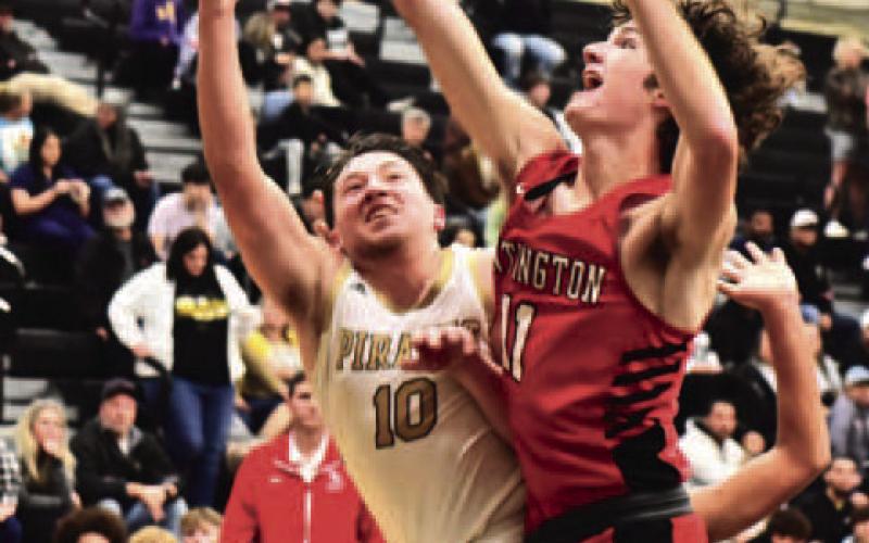 Camden Young’s shot under the net is blocked by a Red Devil in Friday’s varsity basketball game. Photo by Randall Luker