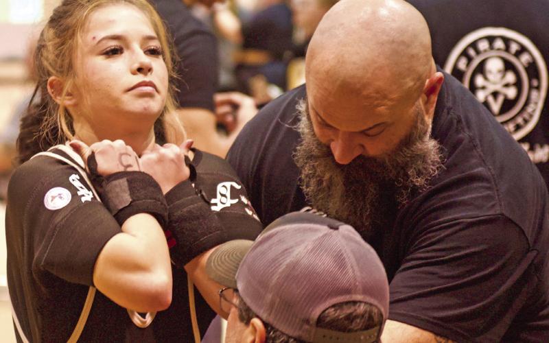 It’s a cinch Lady Pirate Layla Robinson gets a hand with her equipment as she belts up for the bench press at the Nederland High School Powerlifting meet Friday.