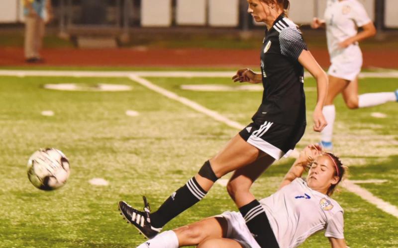 A Bay City Blackcat slides beneath Lady Pirate Jaden Lee in Tuesday’s playoff game.