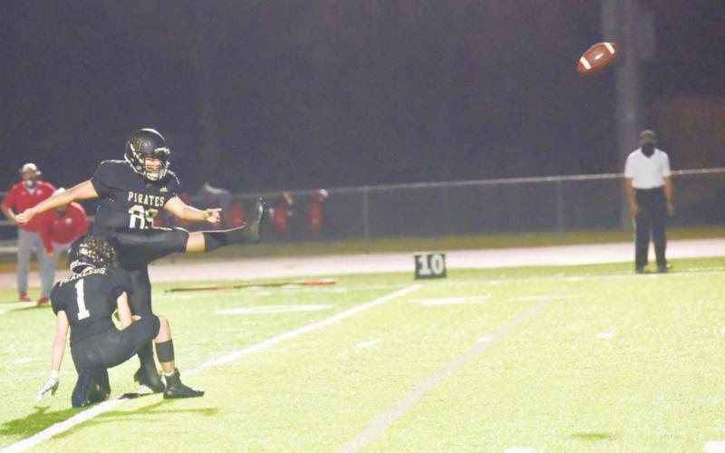 Pirate kicker Aaron Guevara kicks a PAT while Nathan Bullard holds.