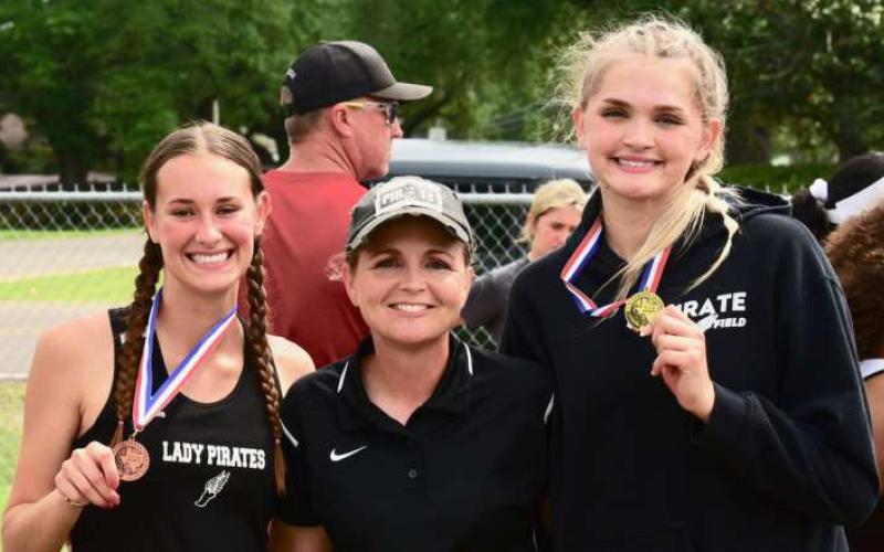 Vidor Head Girls Track Coach Tracy Maines, center, poses with two of Vidor’s district champions, Jaden Lee, left, and Raegan Stephenson, right.