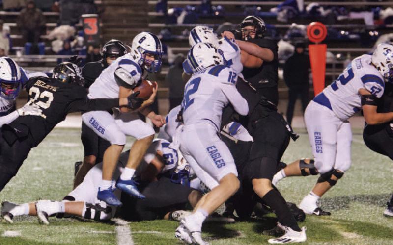 Aidan Villafano reaches for Eagle QB Clint Thurman as he jumps through the line. Photo by Randall Luker