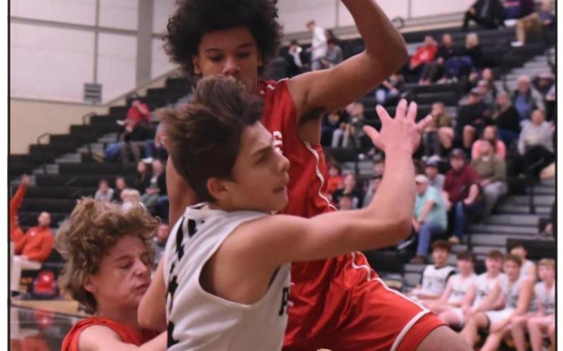 Freshman Pirate Jose Guerrero Evans is fouled by a Raider defender as he goes in for a shot in Tuesday’s district game versus Lumberton. Photo by Randall Luker