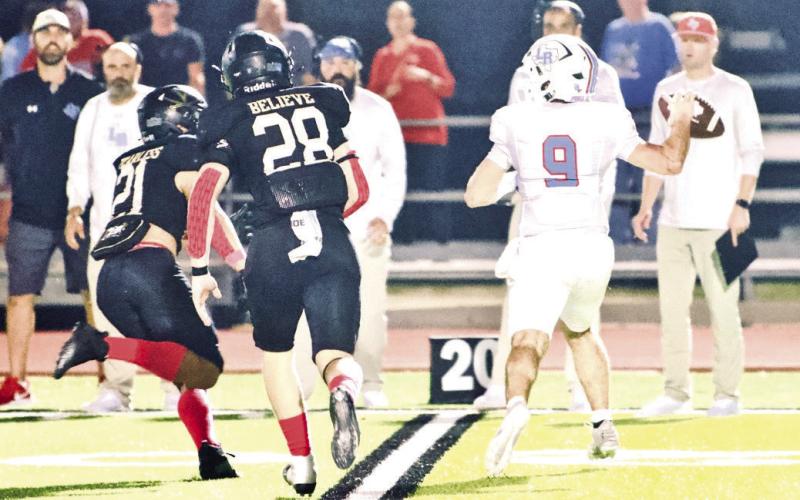 Lumberton QB Lucas Powell is under pressure as Pirate defenders Orrin Cole, #21, and Skylar Stankovich, #28, bear down.