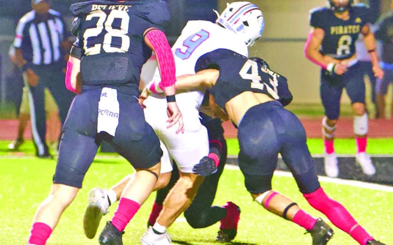 Skylar Stankovich, Brayden Root and an unidentified Pirate defender stop Raider QB Lucas Powell in the Red Zone.