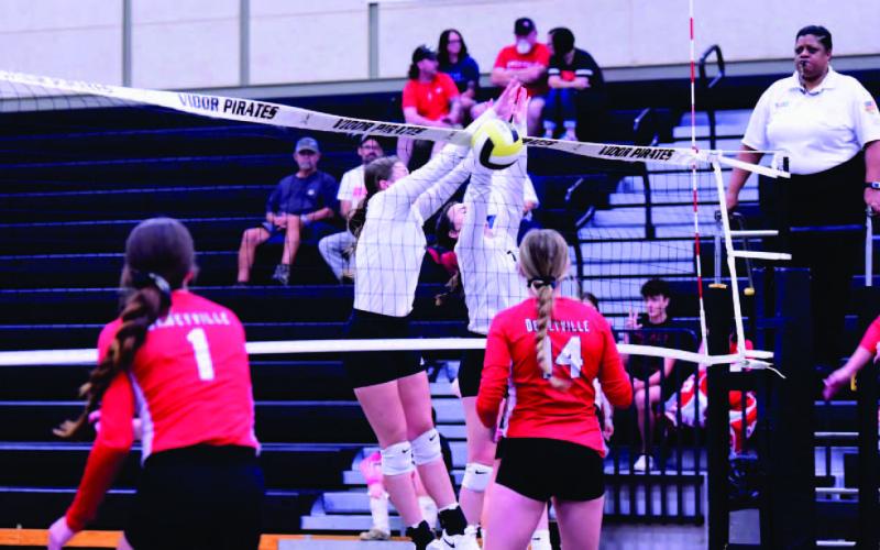 Madison Powell, left center, and Brilie Cornelison, tight center/ block a Deweyville return and score for The Lady Pirates Friday at Pirate gym. All three Vidor Lady Pirate teams defeated Deweyville in straight sets. Photo by Randall Luker