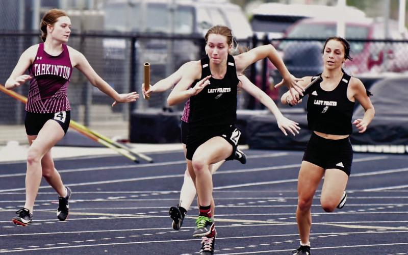 Lady Pirate Jana Baters, far right, hands off the baton to Miley Rice in the 4X100m relay at the Gid Campbell Relays held in Anahuac Thursday. Photo by Randall Luker