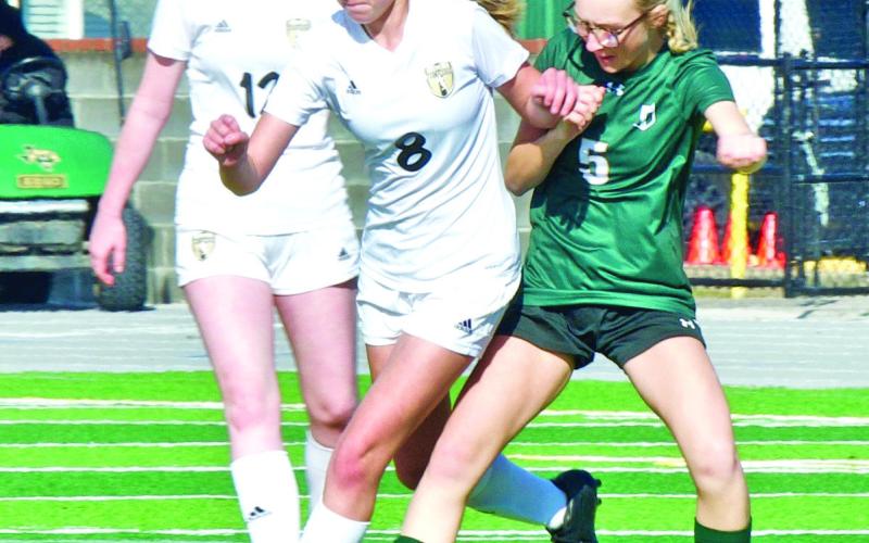 Lady Pirate junior varsity soccer players Alyssa Higgins, #8, and Ashlyn Martin, #12, squeeze past an LCM player to gain possession of the ball Saturday.