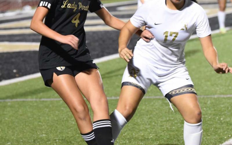 Lady Pirate Kenya Correia maneuvers the ball near the sideline as a Lady Bulldog competes for possession. Photo by Randall Luker