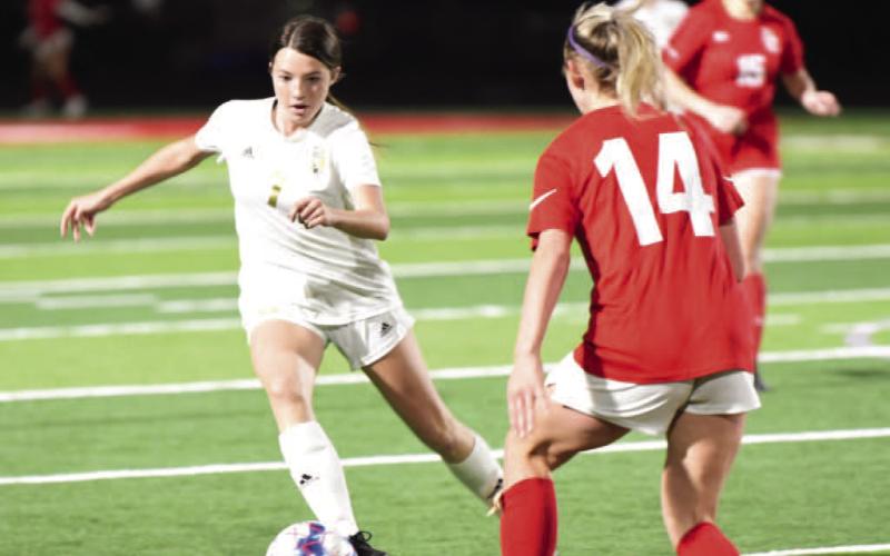 Chloe Post maneuvers past a Lady Cardinal as she approaches the goal in Friday’s varsity district match in Bridge City. Photo by Randall Luker