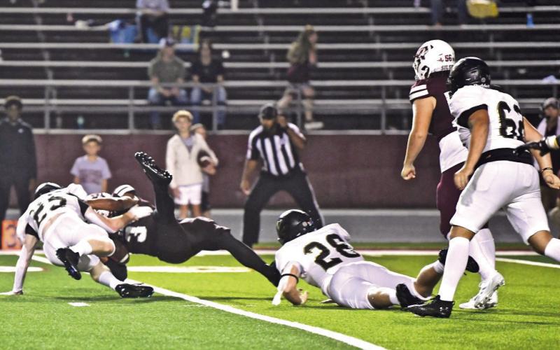 Riley Marlow, #26, and Hyrum Huish, #25, team up to upend a Silsbee ball carrier Friday at Silsbee.