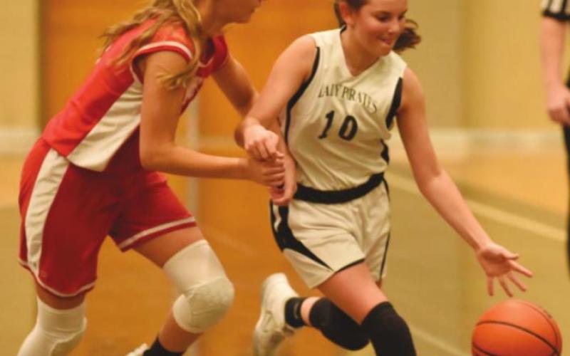 Lady Pirate Allie Williams dribbles past a Lady Cardinal in the 7A game.