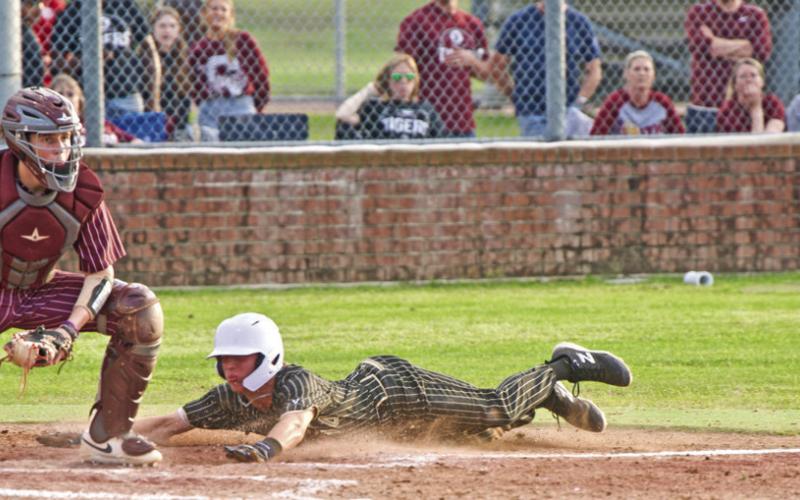 A Pirate slides into home head first to bat the pith to home.
