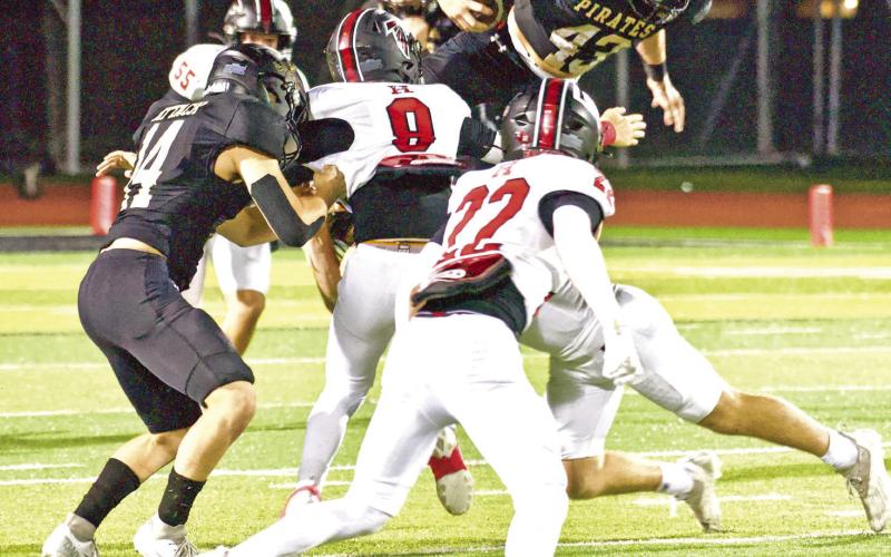 Brayden Root leaps over a Huffman defender in the Pirates’ 49-28 district win on Senior Night.