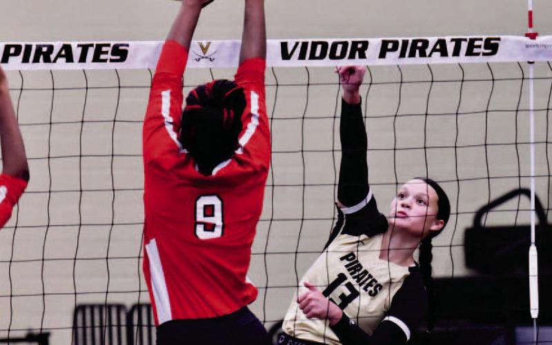 Photo by Randall Luker Varsity Lady Pirate Madison Perkins hits a return between the outstretched arms of two Memorial Lady Titans in Tuesday’s home non-district match.