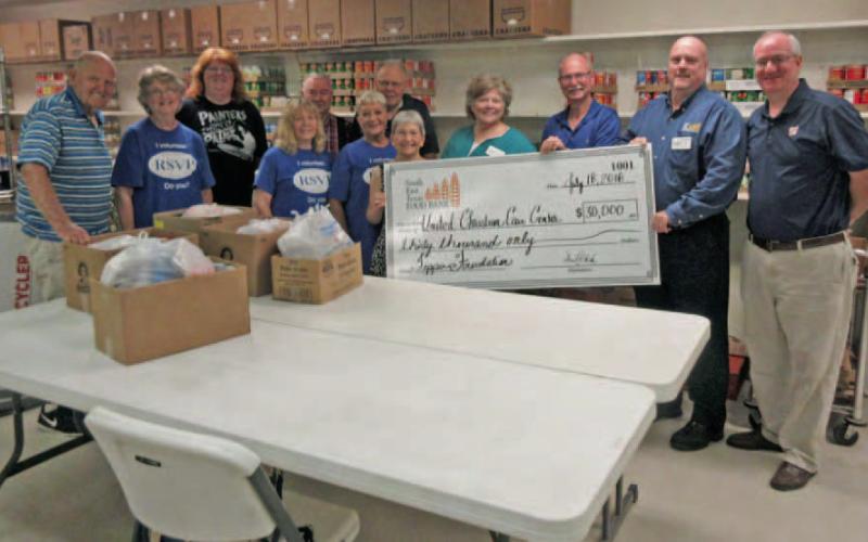 Representatives of the Southeast Texas Food Bank and Feeding America (right) hand a check for $30,000 in grant funds to volunteers (left) at the United Christian Care Center. These funds are intended to help the U.C.C.C. in their ongoing recovery from Hurricane Harvey. Archive Photo