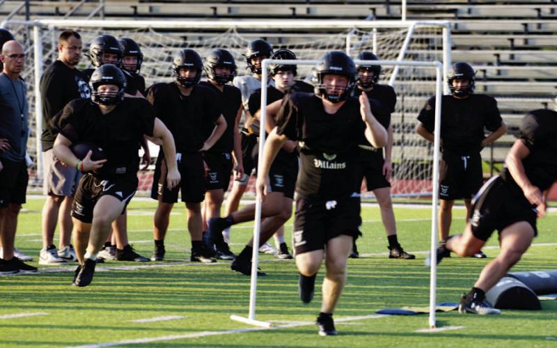 Coaches observe as offensive players practice their patterns and blocking assignments last week.