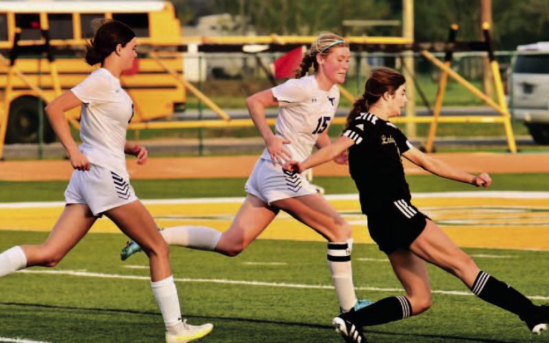 A host of Lady Horns pursue Jordyn Fowler as she takes a shot at the goal in Friday’s bi-district playoff game at East Chambers. Photo by Randall Luker