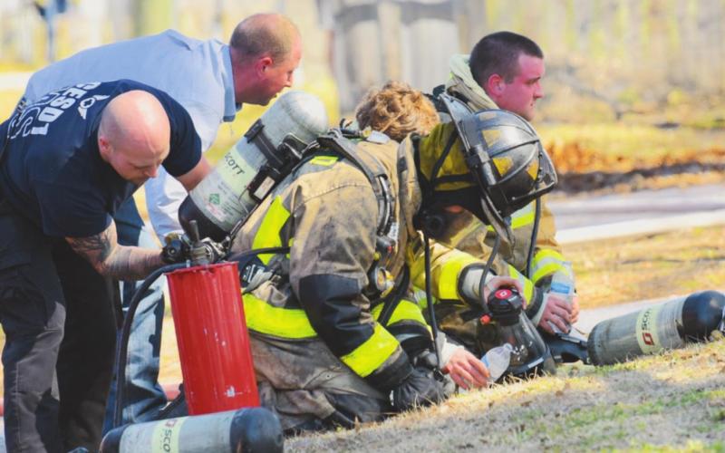 Firefighters with the OCESD#1 have their equipment checked after fighting a structure fire Monday.