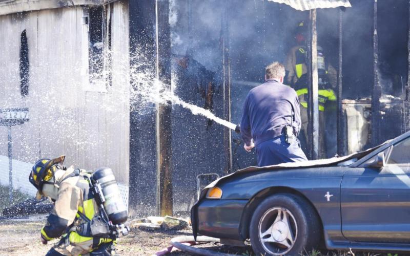 OCESD#1 firemen enter the burning residence as a colleague sprays remaining hot spots.