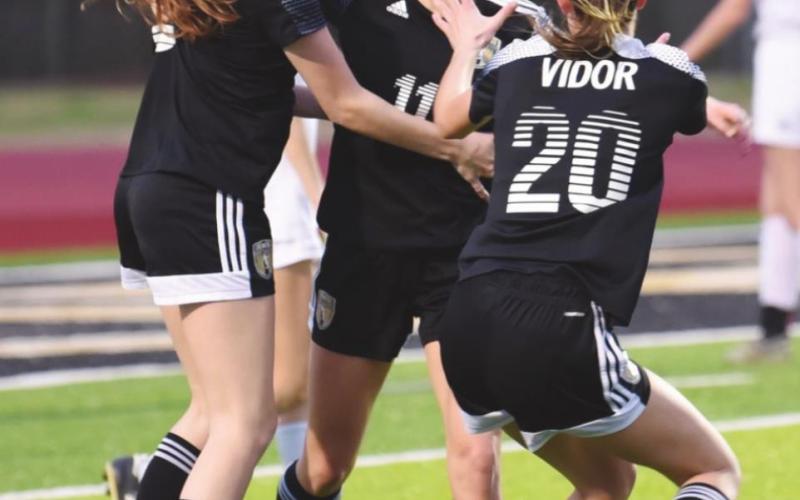 Brooklyn Healy, center, is congratulated by teammates Mary Chilton, left, and Jaden Lee after her 100th career goal.