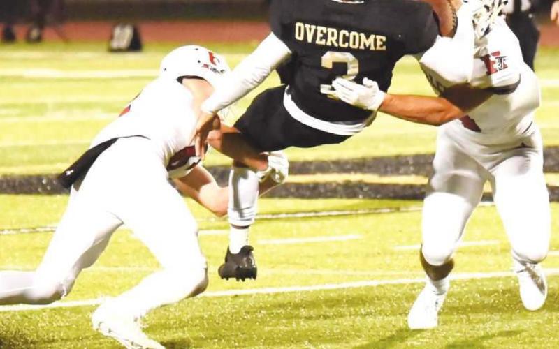Pirate QB Quinten Root hangs on to the ball as he is caught between two Falcon defenders.