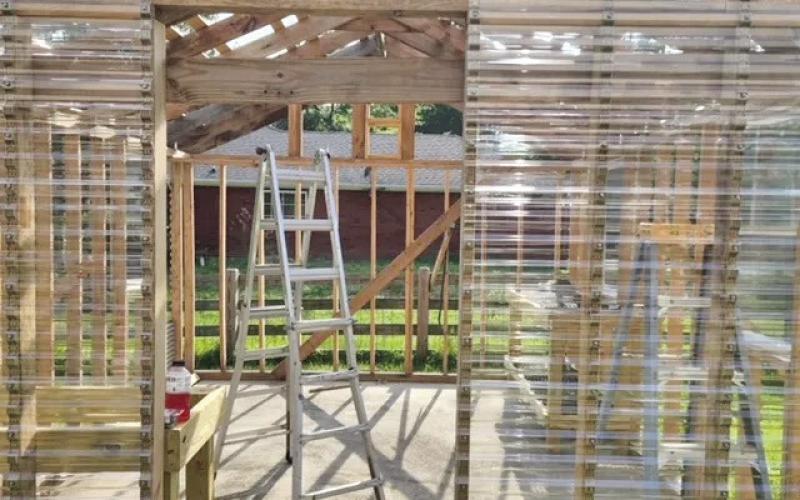 The greenhouse’s wooden framing is complete, and four (double hung) windows installed strategically to maximize ventilation. Two louvres (temperature activated using paraffin) and two exhaust fans (with temperature controllers) are framed located near the roof’s interior apex. Polycarbonate sheeting installation has begun on the entryway (image: John Green).al