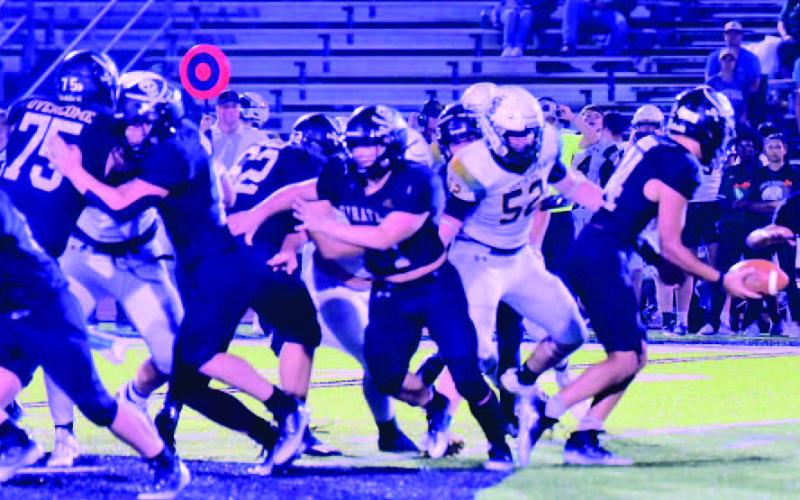 Jarrett Odom hands off the Daigan Venable as a Santa Fe lineman breaks through the offensive lins. Photo by Randall Luker