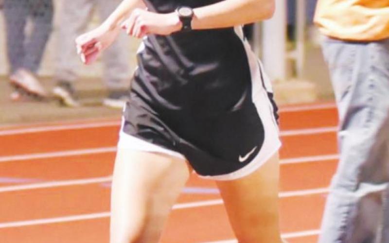 Kendra Long checks her time as she runs in the mile. Long placed second at the district meet..