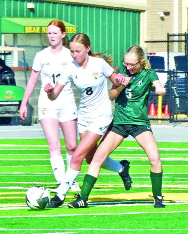 Lady Pirate junior varsity soccer players Alyssa Higgins, #8, and Ashlyn Martin, #12, squeeze past an LCM player to gain possession of the ball Saturday.