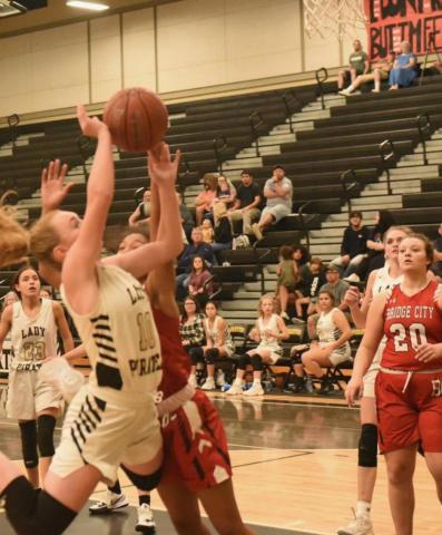 A Bridge City Lady Cardinal fouls Natalie Morrison as she goes for two. Photo by Randall Luker