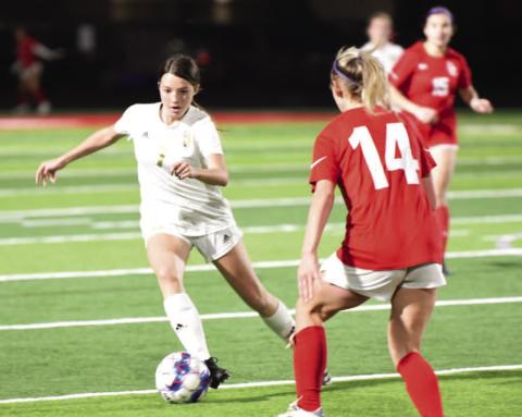 Chloe Post maneuvers past a Lady Cardinal as she approaches the goal in Friday’s varsity district match in Bridge City. Photo by Randall Luker