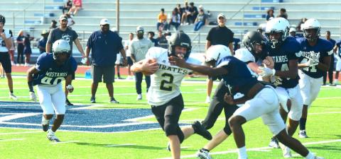 Junior varsity Pirate Brody Bloss looks for running room outside as a Mustang defender tries to stop him.
