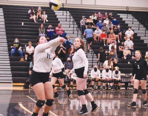 Claire Villadsen, foreground, sets the ball for Rylee Sherman, center.