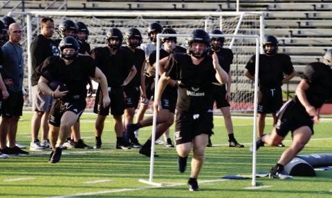 Coaches observe as offensive players practice their patterns and blocking assignments last week.