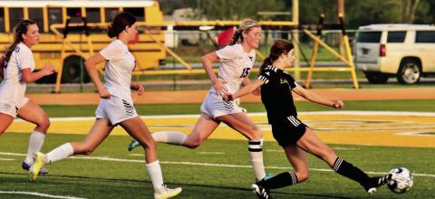 A host of Lady Horns pursue Jordyn Fowler as she takes a shot at the goal in Friday’s bi-district playoff game at East Chambers. Photo by Randall Luker