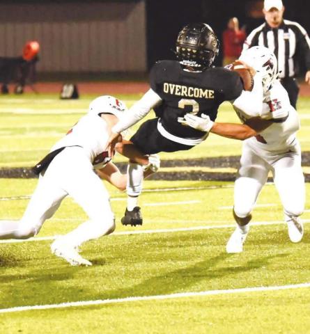 Pirate QB Quinten Root hangs on to the ball as he is caught between two Falcon defenders.