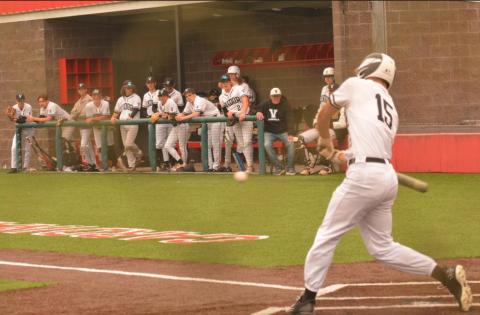 Jarrett Odom starts his swing as Pirate teammates look on from the dugout at the Bridge City baseball tournament. Photo by Randall Luker