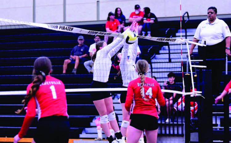 Madison Powell, left center, and Brilie Cornelison, tight center/ block a Deweyville return and score for The Lady Pirates Friday at Pirate gym. All three Vidor Lady Pirate teams defeated Deweyville in straight sets. Photo by Randall Luker