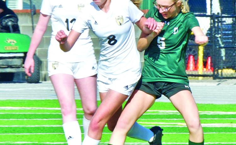 Lady Pirate junior varsity soccer players Alyssa Higgins, #8, and Ashlyn Martin, #12, squeeze past an LCM player to gain possession of the ball Saturday.