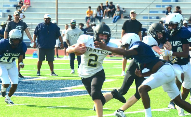 Junior varsity Pirate Brody Bloss looks for running room outside as a Mustang defender tries to stop him.