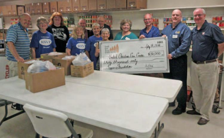Representatives of the Southeast Texas Food Bank and Feeding America (right) hand a check for $30,000 in grant funds to volunteers (left) at the United Christian Care Center. These funds are intended to help the U.C.C.C. in their ongoing recovery from Hurricane Harvey. Archive Photo