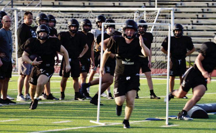 Coaches observe as offensive players practice their patterns and blocking assignments last week.