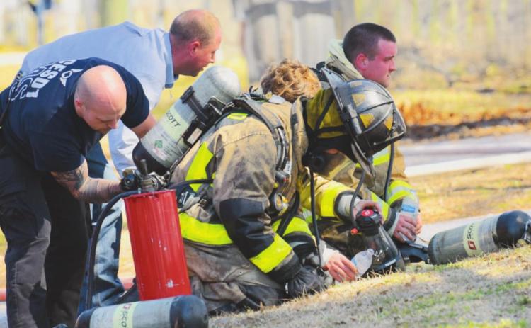 Firefighters with the OCESD#1 have their equipment checked after fighting a structure fire Monday.