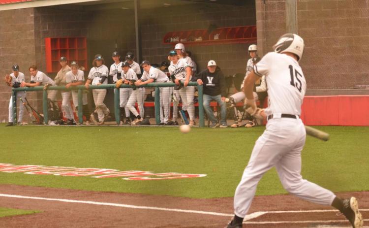 Jarrett Odom starts his swing as Pirate teammates look on from the dugout at the Bridge City baseball tournament. Photo by Randall Luker